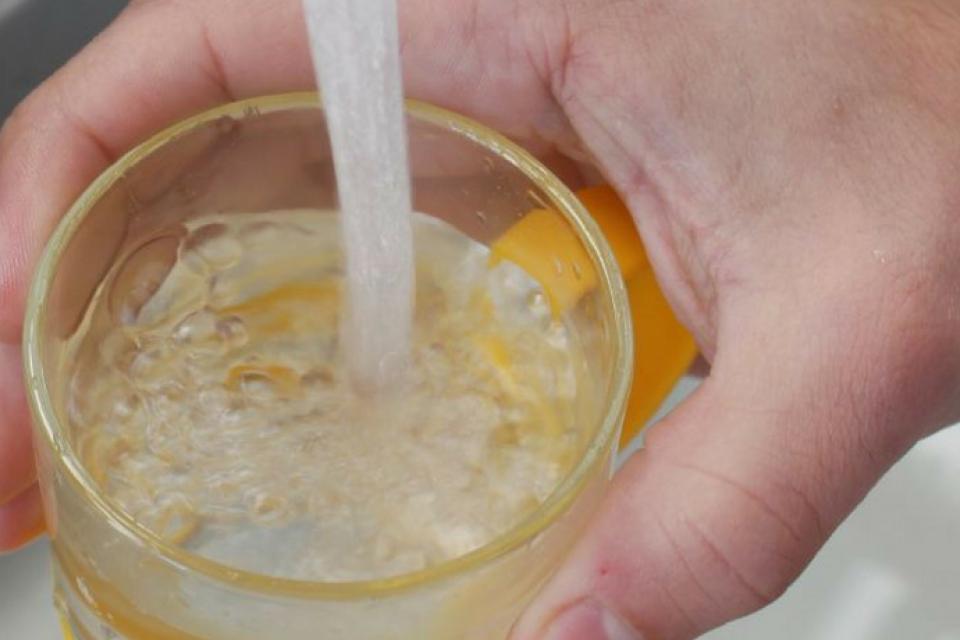 compteur eau.jpg Vue d'une main d'une personne se servant un verre d'eau au robinet.