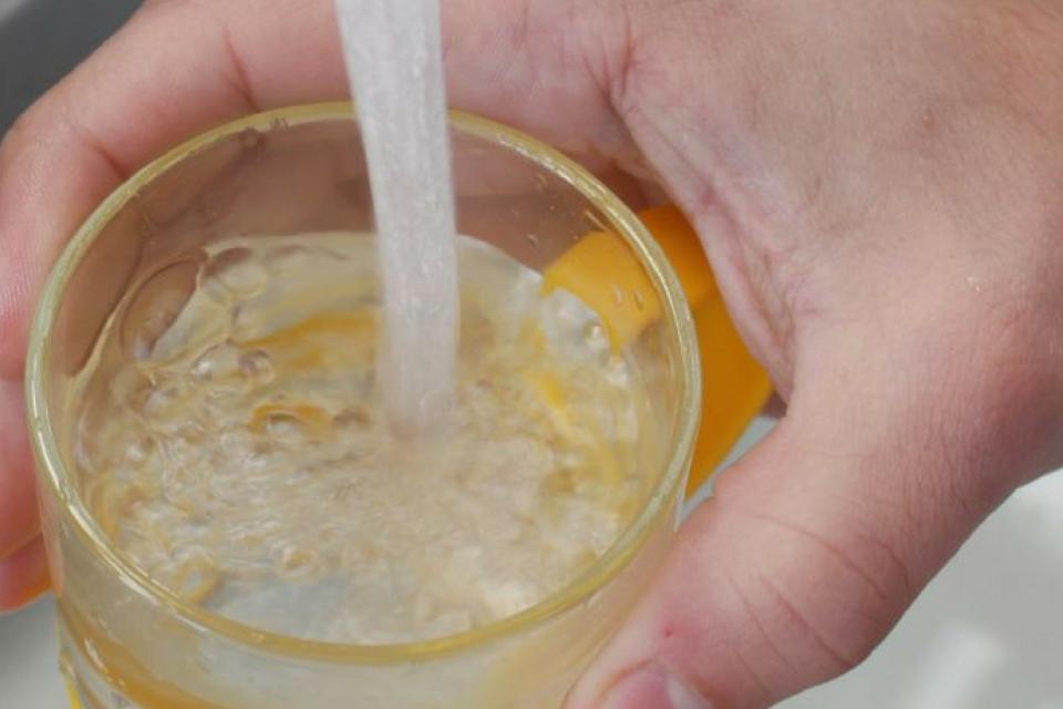 Vue d'une main d'une personne se servant un verre d'eau au robinet.