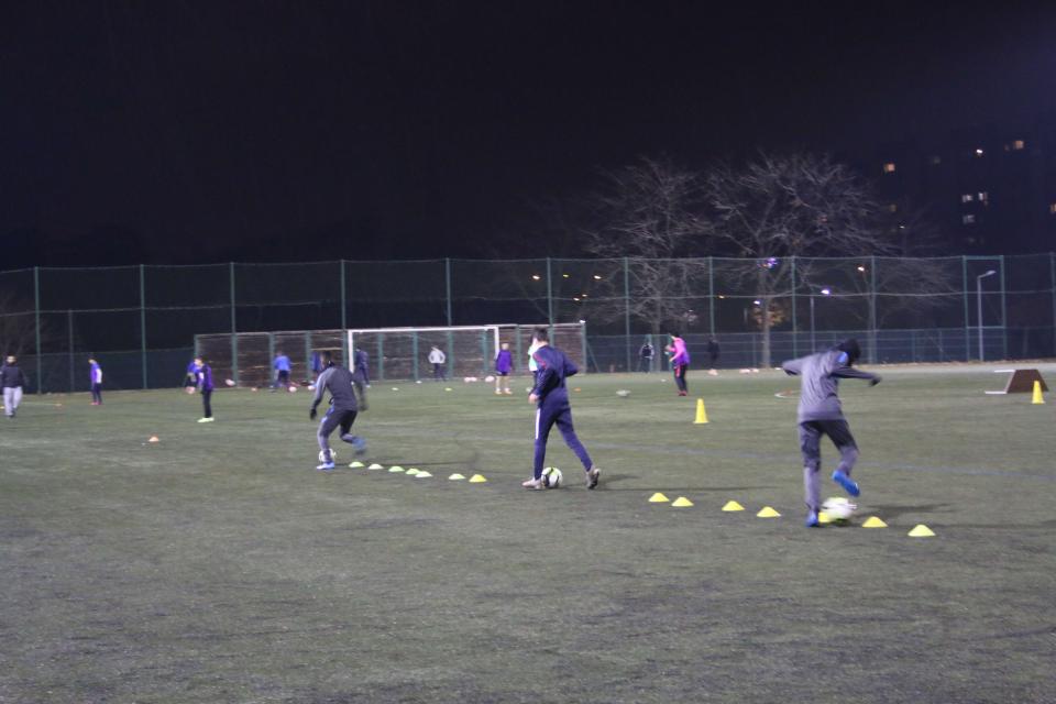 Les joueurs s'entraînent sur le terrai, chacun avec son ballon.