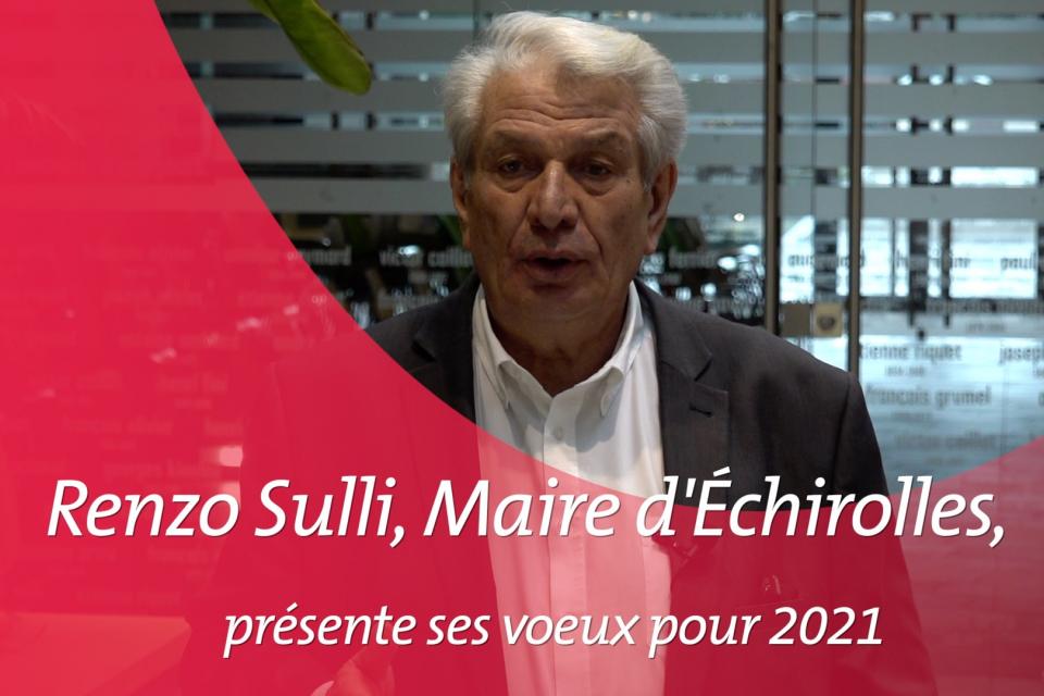 Voeux du maire 2021 Le Maire d'Echirolles se tient en costume noir et chemise blanche, devant la salle des mariages. Il présente ses voeux aux échirollois-es pour l'année 2021. Sur cette image, une contre forme arrondie rose (charte graphique des vidéos de la ville) introduit la vidéo.
