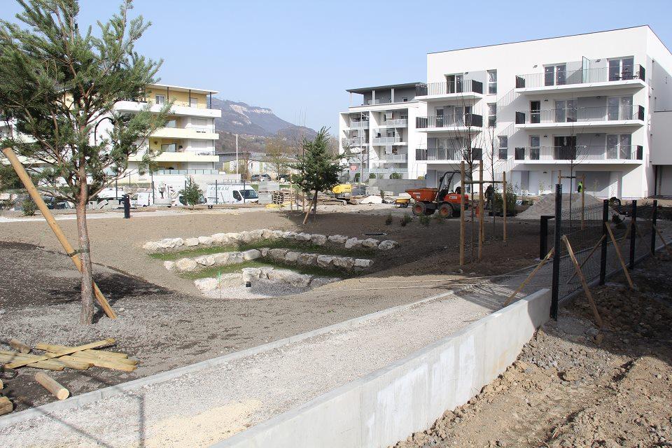 Vue sur le programme immobilier Open set. Un petit jardin est en cours d'aménagement au milieu de plusieurs immeubles.