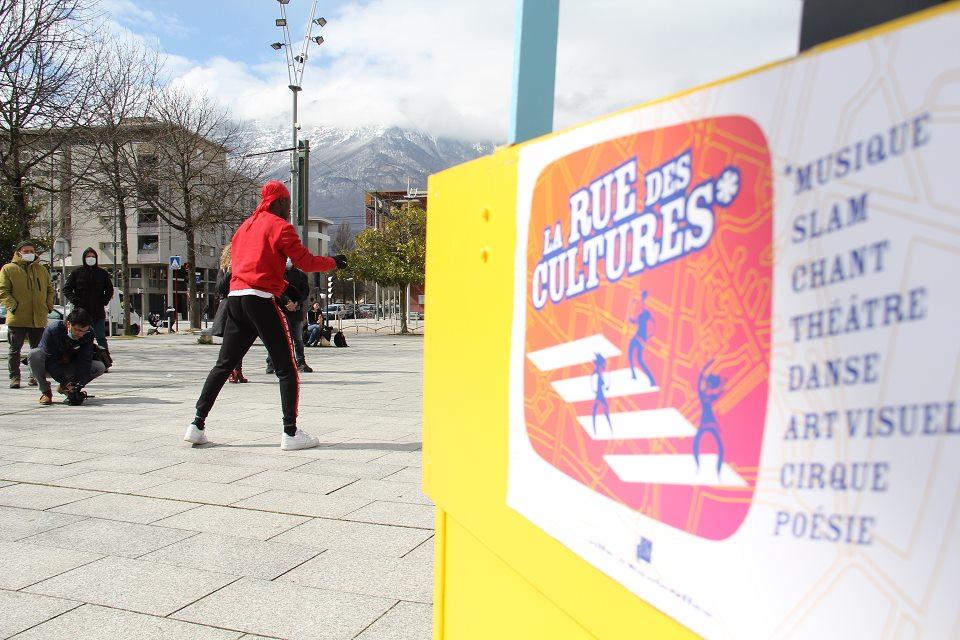 La Rue des cultures du jeudi 18 mars Alan, danseur du groupe Soo7kill, danse sur la place des Cinq Fontaines, le triporteur de La Rue des cultures au premier plan.