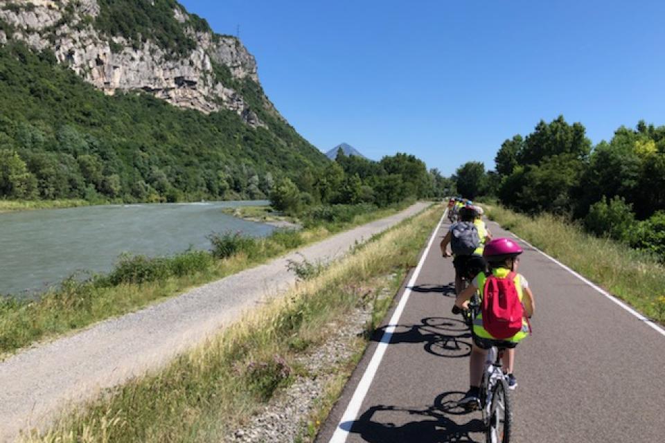 Sortie à vélo d'évade Plusieurs enfants roulent à vélo sur une piste cyclable. La photo est prise depuis la fin de la file. Tous les enfants portent des gilets jaunes par mesure de sécurité.