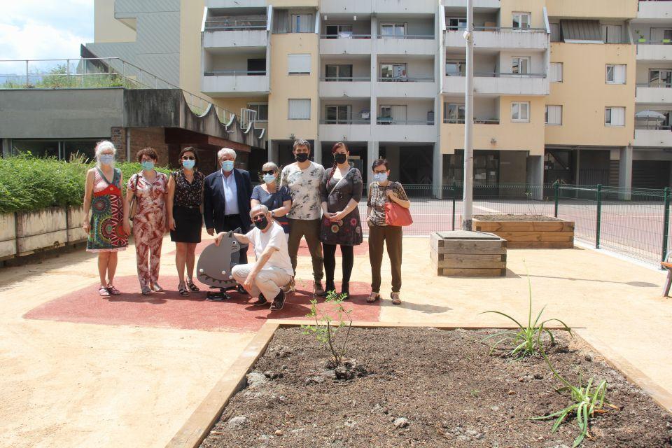 Photo du nouvel espace détente  place des Vosges. Les élu-es posent dans le nouvel espace détente. Autour d'eux nous voyons des bancs, des jeux pour enfants et des bacs pour des plantes.