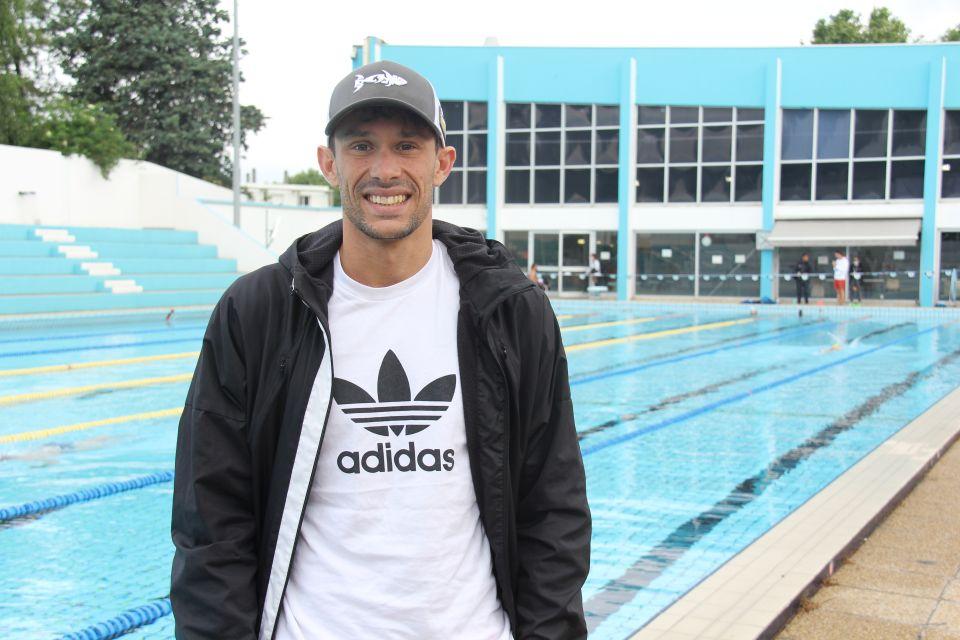 Photo de Dorian Coninx, habillé au bord de la piscine.