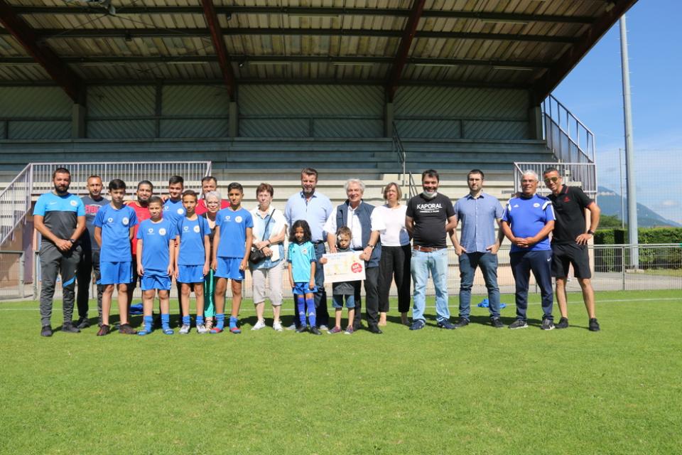 Remise des premiers Chèques sport avec les élus de la Ville, OSE et le FCE Photo prise à l'occasion de la remise des premiers Chèques sport avec les élus de la Ville, OSE et le FCE. Nous voyons le maire et les élu-es qui posent sur le terrain de foot avec les jeunes joueurs et les encadrants du club de foot.