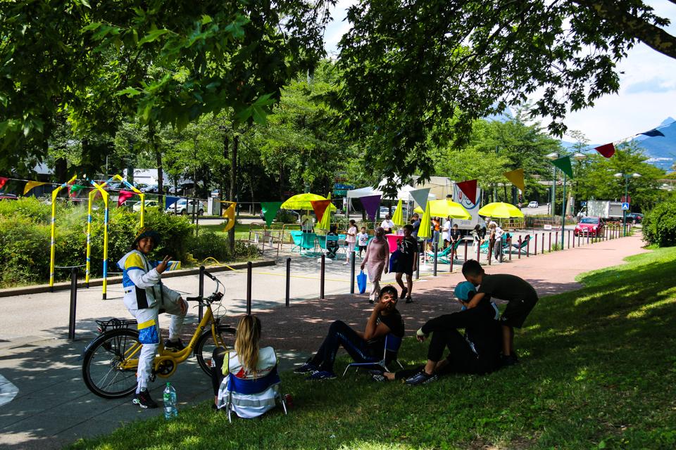 Photo de la contre-allée de l'avenue des États-Généraux, sans voiture pendant quelques jours accueillait des animations. Nous voyons des stands, des parasols de couleurs, des jeunes assis dans l'herbe.