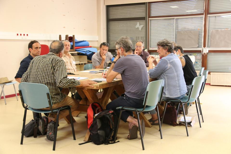 Photo prise lors du Parlement culturel.  Une dizaine de personne sont assis autour d'une table et échangent autour des enjeux culturels sur le territoire.