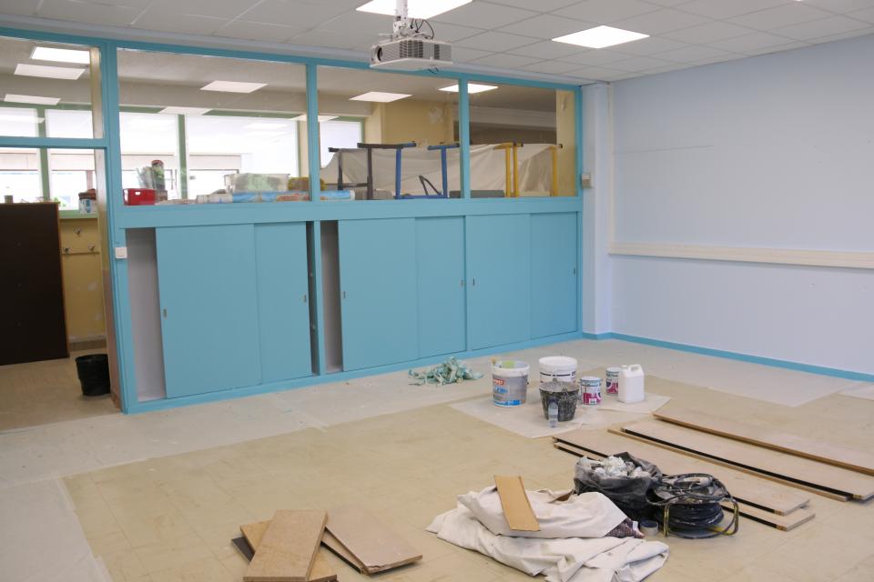 Photo des travaux dans l'école Jean Moulin avec un mur qui vient d'être repeint et du matériel de chantier au sol